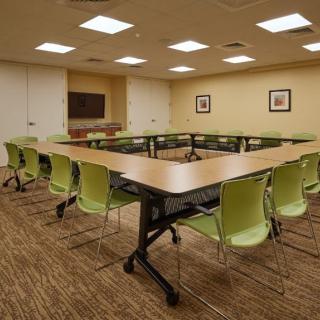 A conference room with a U-shaped table arrangement and green chairs.