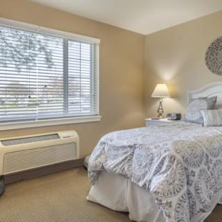 A cozy bedroom with a neatly made bed, a bedside lamp, and a large window.
