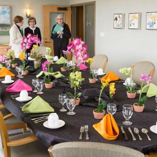 A beautifully arranged dining table with colorful flowers and elegant table settings, ready for a special event.
