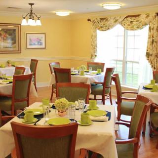 A warmly lit dining area with neatly arranged tables and chairs, complete with table settings.