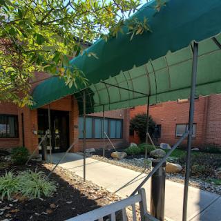 A welcoming entrance with a green canopy and landscaped surroundings.