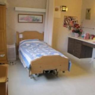A hospital room with a single bed, medical equipment, and decor on the walls.