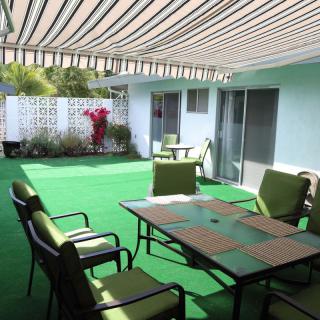 A covered patio area with green carpet, featuring outdoor seating and a table.