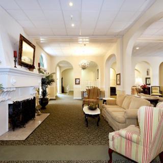 A spacious and elegantly decorated living room with a classic fireplace and comfortable seating.