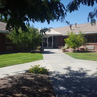 A serene view of a residential building with a well-maintained pathway and lush greenery.