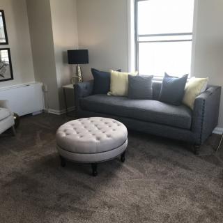 A cozy living room with a modern sofa, ottoman, and decorative cushions.