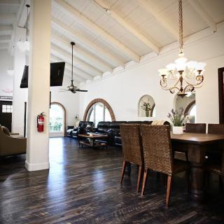 A spacious living and dining area with high ceilings, featuring a wooden floor and elegant chandelier.