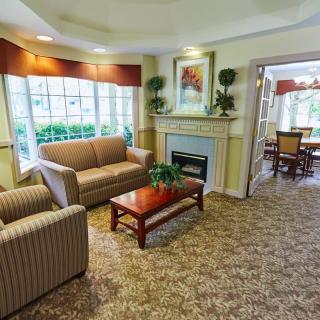 A cozy living room with a sofa, armchair, and fireplace.