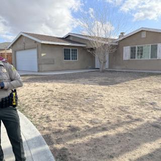 A law enforcement officer standing outside a residential home.