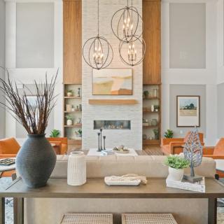 A modern living room with a stylish design featuring hanging chandeliers, artwork, and elegant furniture.