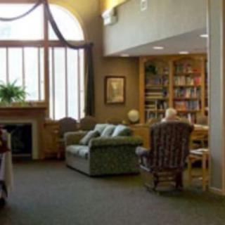 A cozy reading area in a library with an armchair, bookshelf, and a large window.