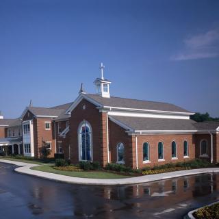 A brick church with a prominent steeple against a clear blue sky.