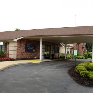 A brick building with a driveway and landscaped entrance.