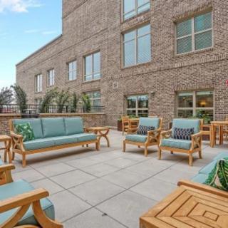 A spacious outdoor patio with comfortable seating arrangements against a brick building backdrop.