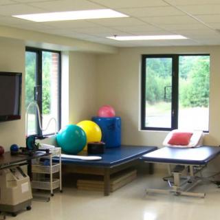 A well-equipped physical therapy room with exercise balls and tables.