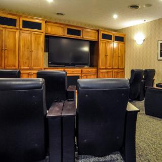 A luxurious home theater with leather seating and a large TV screen.