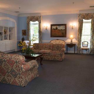 A traditionally decorated living room with floral-patterned sofas, a carpet, and classic furnishings.