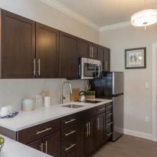 A modern kitchen with dark cabinets and stainless steel appliances.