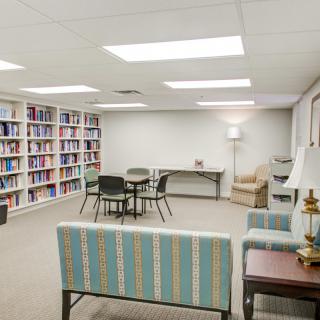 A quiet library space with bookshelves, seating, and tables for study or reading.
