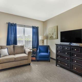 A cozy living room with a sofa, armchair, and a television on a dresser.