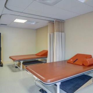 A clinic treatment room with two medical beds and privacy curtains.