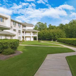 A residential building surrounded by a well-maintained lawn and pathway under a bright, blue sky.