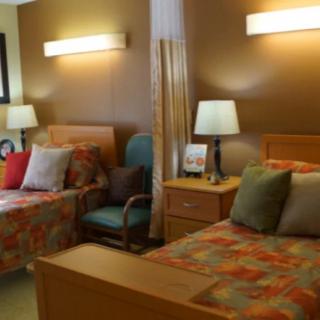 A cozy bedroom featuring two beds with colorful bedding, bedside lamps, and a nightstand.