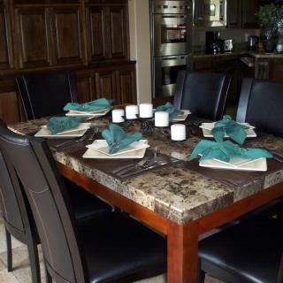 A well-set dining table with teal napkins and black chairs.