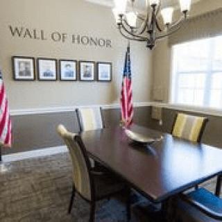 A conference room with a 'Wall of Honor' display, featuring photographs and two American flags.