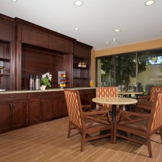 A modern dining area with wooden furniture and cabinetry, featuring a round table and upholstered chairs.