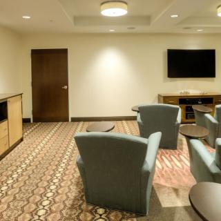 A cozy lounge area with chairs, a table, and a wall-mounted television.