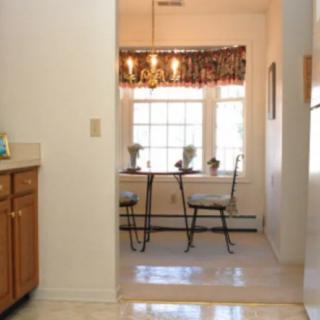 A view from the kitchen into a small dining area with a table, chairs, and large windows.