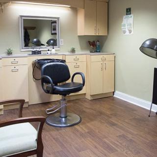 An empty salon with a styling chair, mirror, and hair dryer.