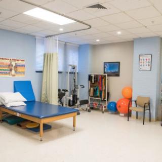 A physical therapy room equipped with treatment tables, therapy balls, and exercise equipment.