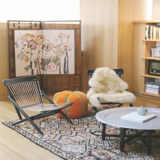 A cozy living room setup featuring a stylish chair, soft rug, and decorative artwork.