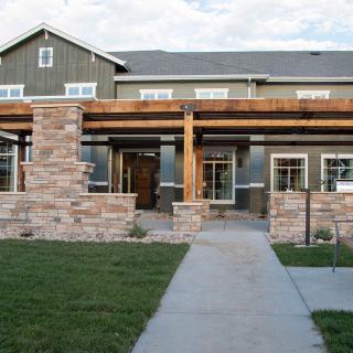 A modern two-story house with a stone facade and a wooden pergola at the entrance.