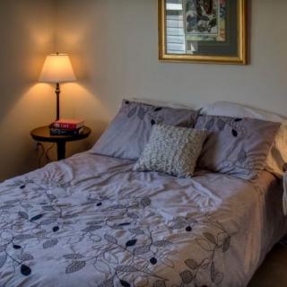 A cozy bedroom with a neatly made bed, decorative pillows, and a warm lamp on the side table.