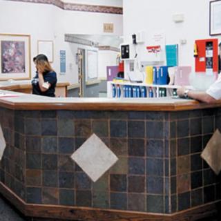 Two people at a reception desk in a lobby area.