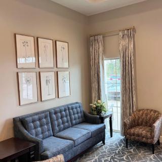 A cozy living room with a blue sofa, armchair, and framed artwork on the wall.