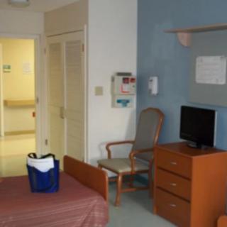 A hospital room with a bed, television, and medical equipment.