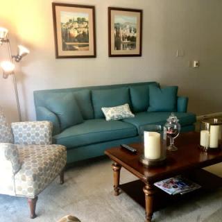 Cozy living room with a teal sofa, patterned armchair, and a wooden coffee table adorned with candles.