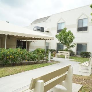 A peaceful outdoor area featuring benches, a pathway, and a garden adjacent to a residential building.