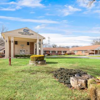 A serene view of a motel surrounded by lush greenery under a clear blue sky.