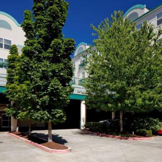The image shows a building with trees in the foreground on a clear day.