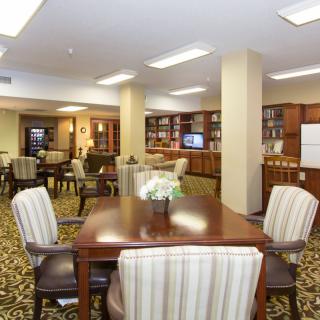 A cozy library interior with bookshelves, tables, and chairs arranged for reading and relaxation.