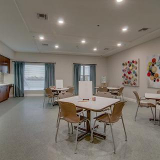 A modern and spacious dining area with tables and chairs, featuring contemporary artwork and soft lighting.