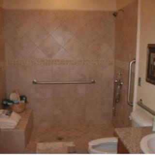 A bathroom featuring a walk-in shower, tiled walls, and accessible handrails.