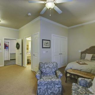 A cozy bedroom with a bed, armchair, and ceiling fan.