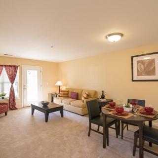 A cozy living room with a dining area, featuring a sofa, coffee table, and dining table with chairs.