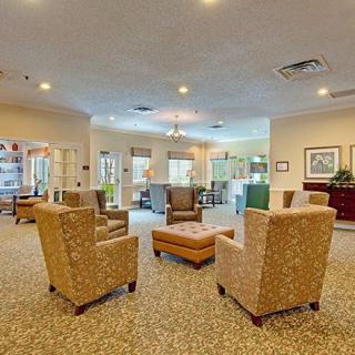 A cozy lobby area featuring armchairs arranged around a central ottoman, with ample natural light and open space.